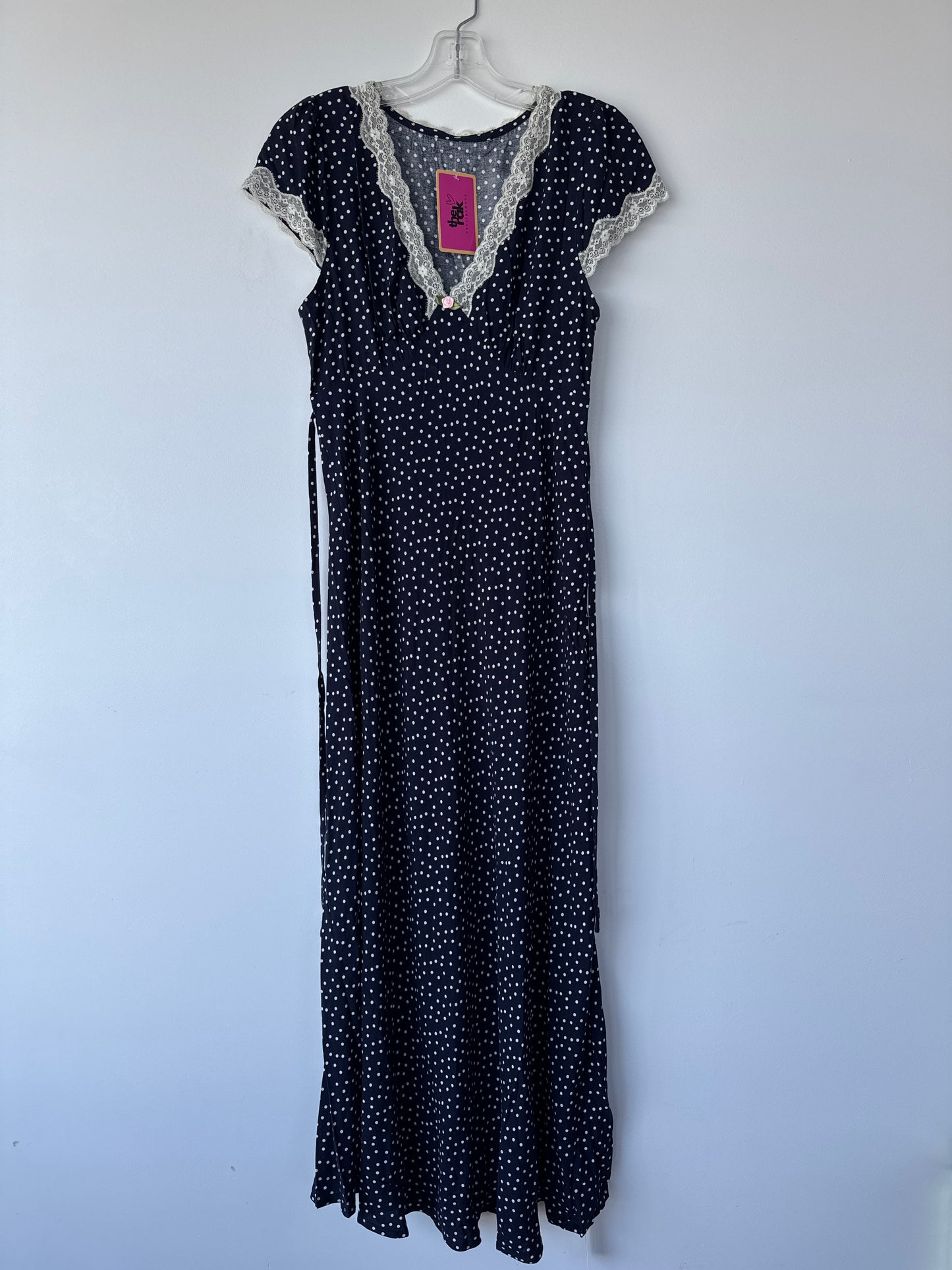 A black maxi dress with a white polka dot pattern, featuring a lace-trimmed V-neckline and short sleeves, hanging on a white hanger against a plain light gray wall.sherwood park secondhand, preloved, consignment, edmonton