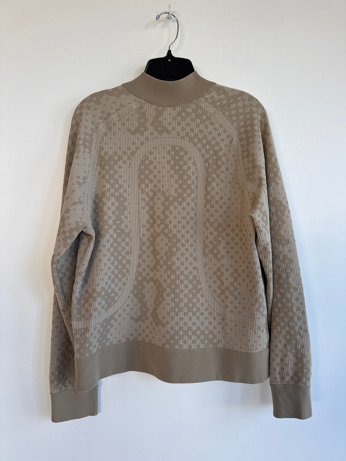 A taupe knit mock-neck sweater with a geometric pattern, hanging on a black hanger against a plain white wall. Rare Lululemon Zip Up. So Cool. Sherwood Park consignment, Sherwood Park shopping, consignment store Sherwood Park, Edmonton consignment, secondhand shopping, secondhand clothing, women’s consignment, women’s clothing consignment, curated consignment, quality secondhand clothing, pre-loved clothing, thrift shopping, sustainable fashion, local shopping, Alberta consignment