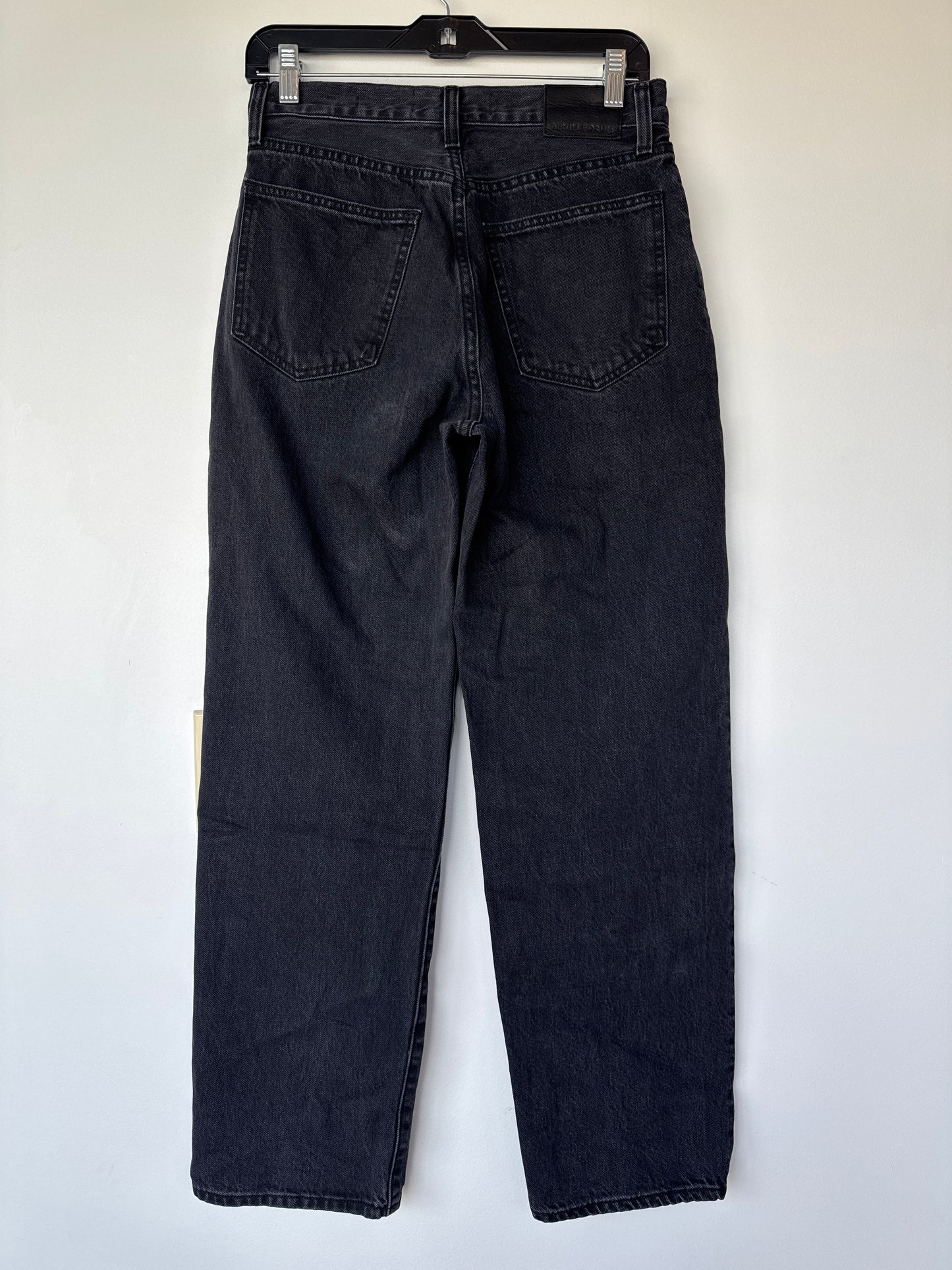 A pair of dark washed denim jeans shown from the back, hanging on a black hanger against a plain white wall. premium denim at a cheaper price, aritzia, Edmonton consignment, women’s clothing consignment