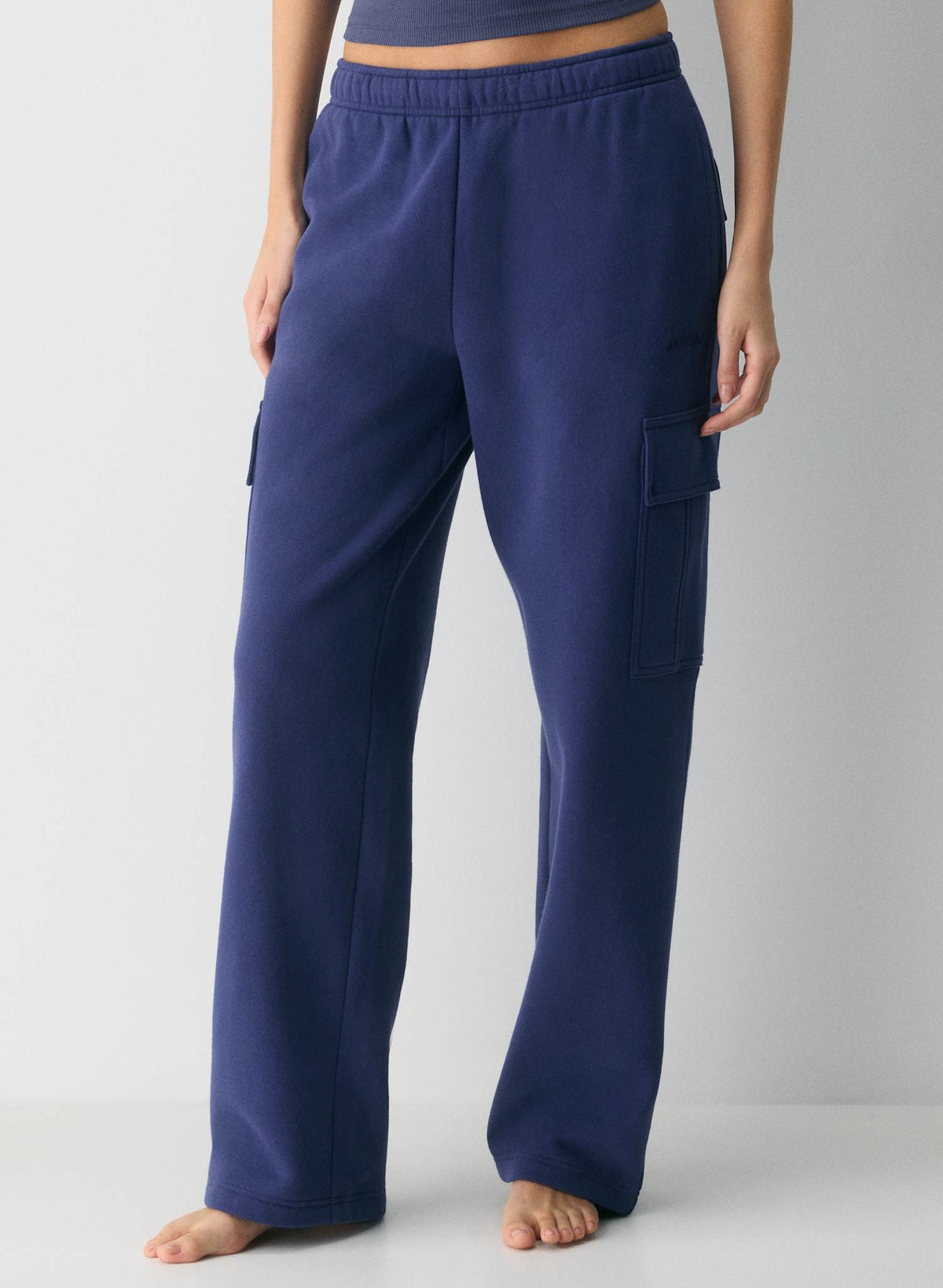 A person wearing Aritzia navy blue wide-leg cargo sweatpants, shown from the waist down against a light gray studio background. At he RAK. Edmonton Womens Consignment Store. Sherwood Park Alberta. Aritzia.