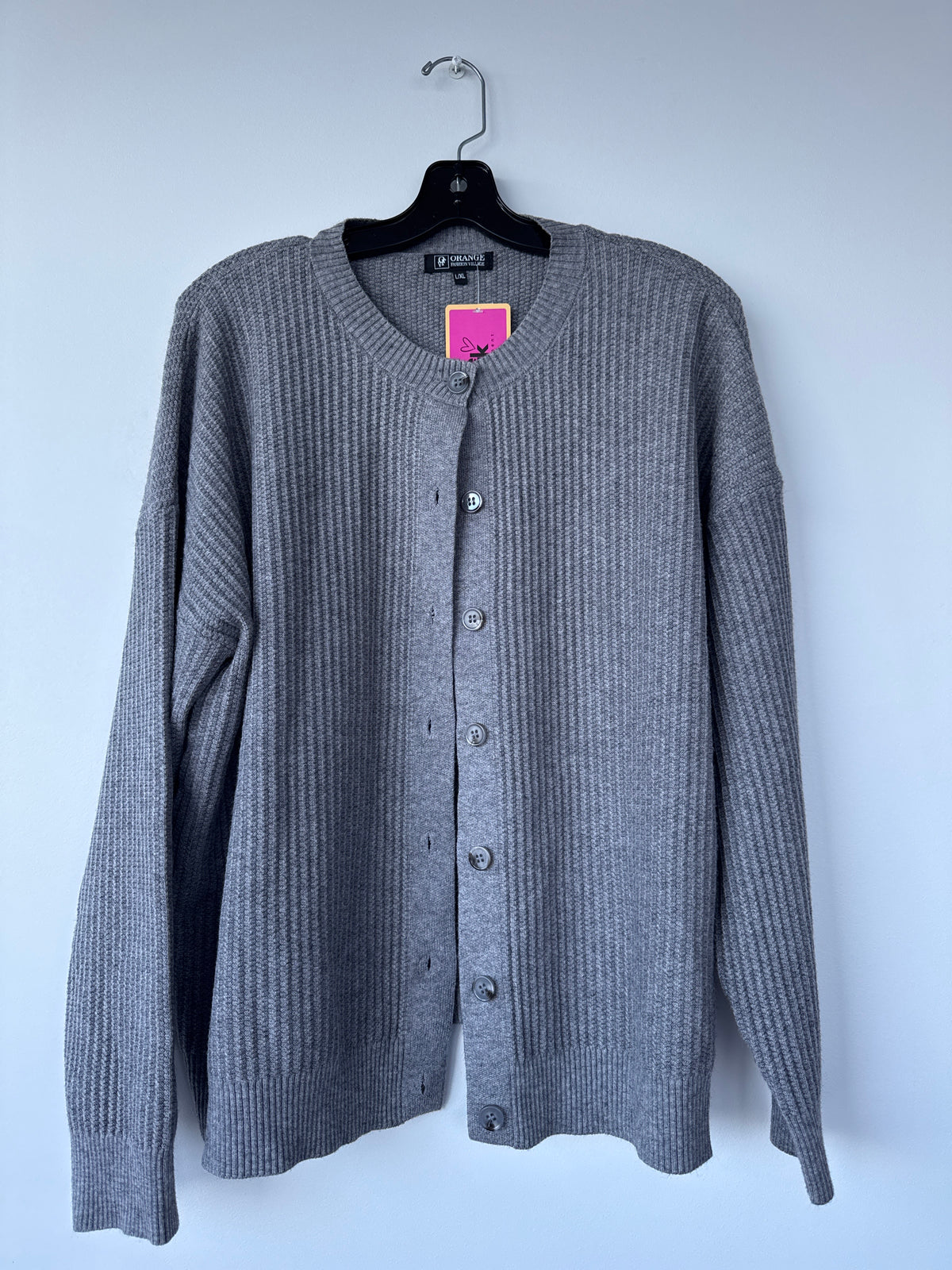 A gray ribbed knit cardigan sweater hanging on a black hanger against a light gray wall, featuring a round neckline and front button closure. 
edmonton consignment, sherwood park consignment, secondhand, preloved, yeg, shpk