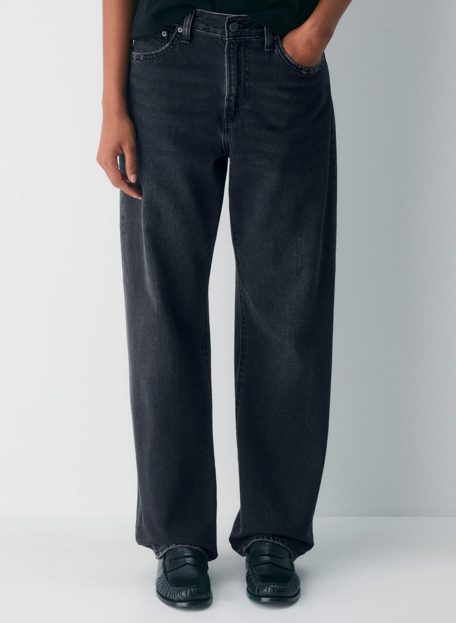 A person wearing dark charcoal wide-leg denim jeans with black shoes, shown from the waist down against a light gray studio background. premium denim at a cheaper price, aritzia, Edmonton consignment, women’s clothing consignment
