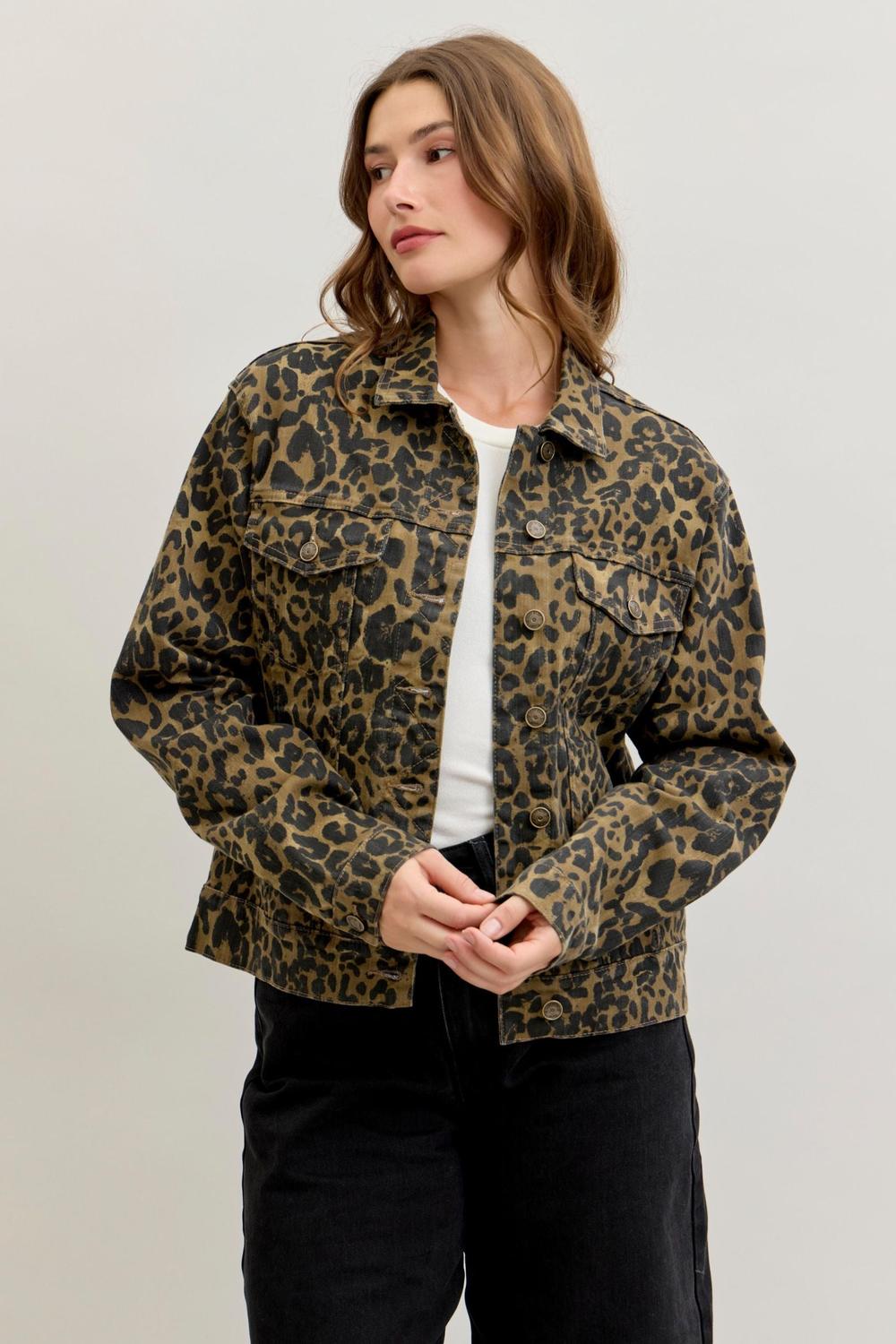 A woman wearing a cropped leopard-print jacket over a white top and black pants, standing against a plain light gray studio background. Sherwood Park consignment, Sherwood Park shopping, consignment store Sherwood Park, Edmonton consignment, secondhand shopping, secondhand clothing, women’s consignment, women’s clothing consignment, curated consignment, quality secondhand clothing, pre-loved clothing, thrift shopping, sustainable fashion, local shopping, Alberta consignment. Judy Blue denim jacket, leopard 