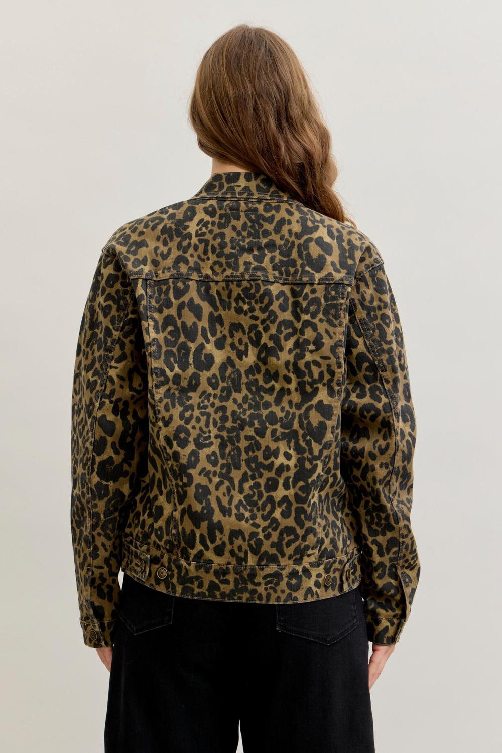 A person viewed from the back wearing a leopard-print jacket with black pants, photographed against a plain light gray studio background. Judy Blue leopard print denim jacket. Sherwood Park consignment, Sherwood Park shopping, consignment store Sherwood Park, Edmonton consignment, secondhand shopping, secondhand clothing, women’s consignment, women’s clothing consignment, curated consignment, quality secondhand clothing, pre-loved clothing, thrift shopping, sustainable fashion, local shopping, Alberta consi
