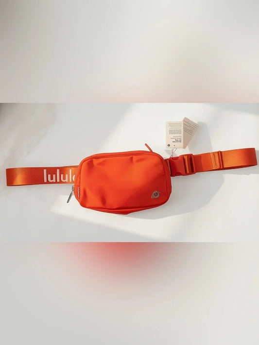 An orange Lululemon waist bag with a matching orange adjustable strap, shown with its retail tag on a white background.