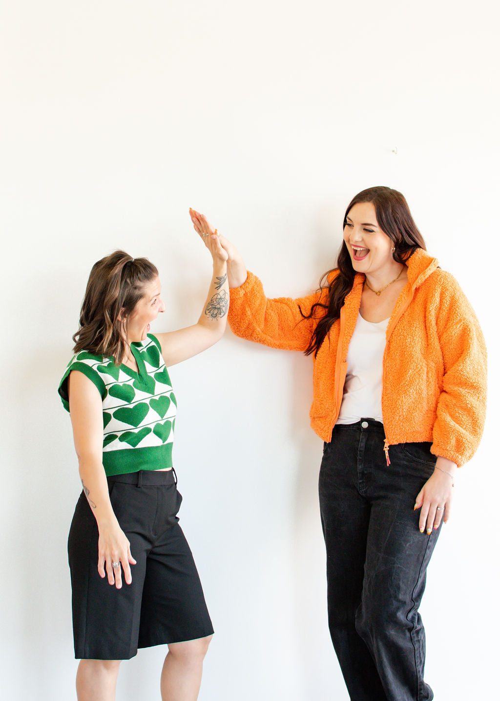 RAK owners Dara Eckel and Dawn-Marie Jack high fiving their consignment boutique in green and orange fun fashion