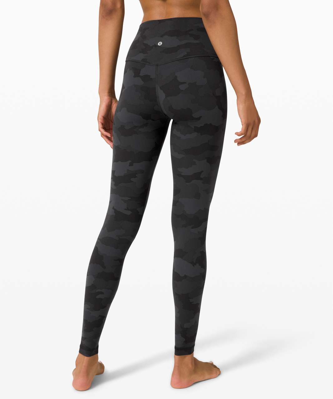 A model from the back wearing high-waisted leggings with a dark gray and black camouflage pattern, set against a plain white studio background. edmonton, sherwood park, secondhand lululemon, consignment shop, consignment store, preloved clothes, alberta secondhand lululemon