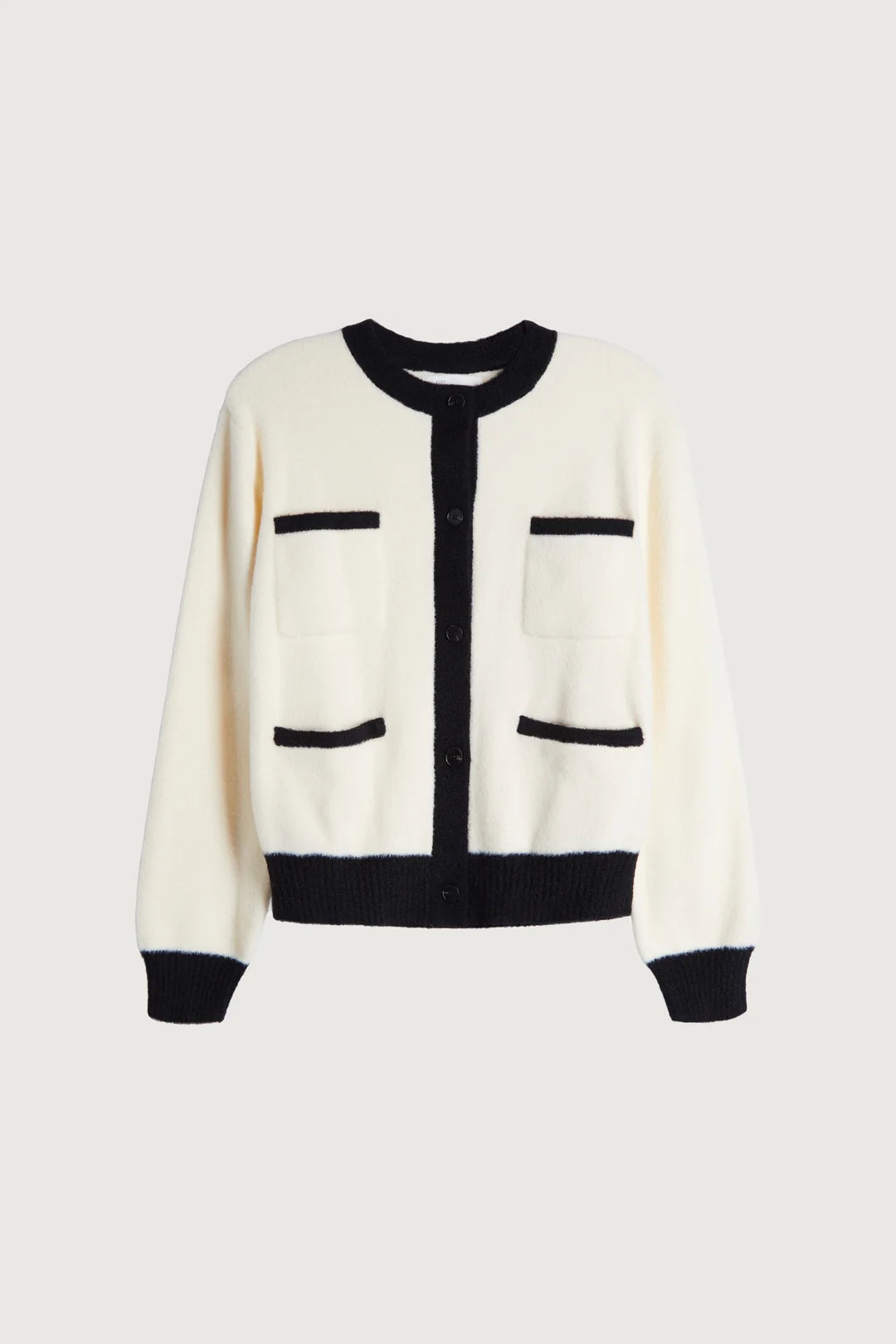 An off-white knit Oak + Fort cardigan with black trim, featuring a black crew neck, black button placket, black ribbed hem and cuffs, and two front patch pockets with black trim, shown against a light gray background. Womens consignment, edmonton preloved