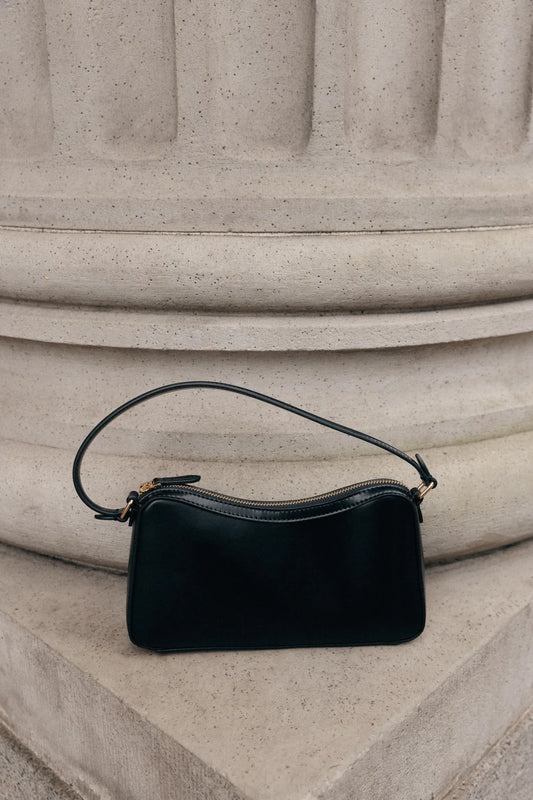 Black handbag on a stone surface. Oak + Fort Handbag. Preloved Oak + Fort. Sherwood Park.